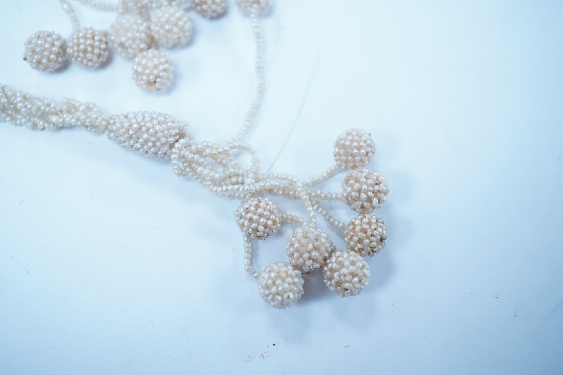 An antique multi strand seed pearl cluster set sautoir necklace, with spherical bead terminals, 56cm. Condition - fair to good